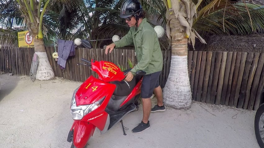 Michael getting on their rental scooter to explore the island of Cozumel, one of the best things to do in Cozumel